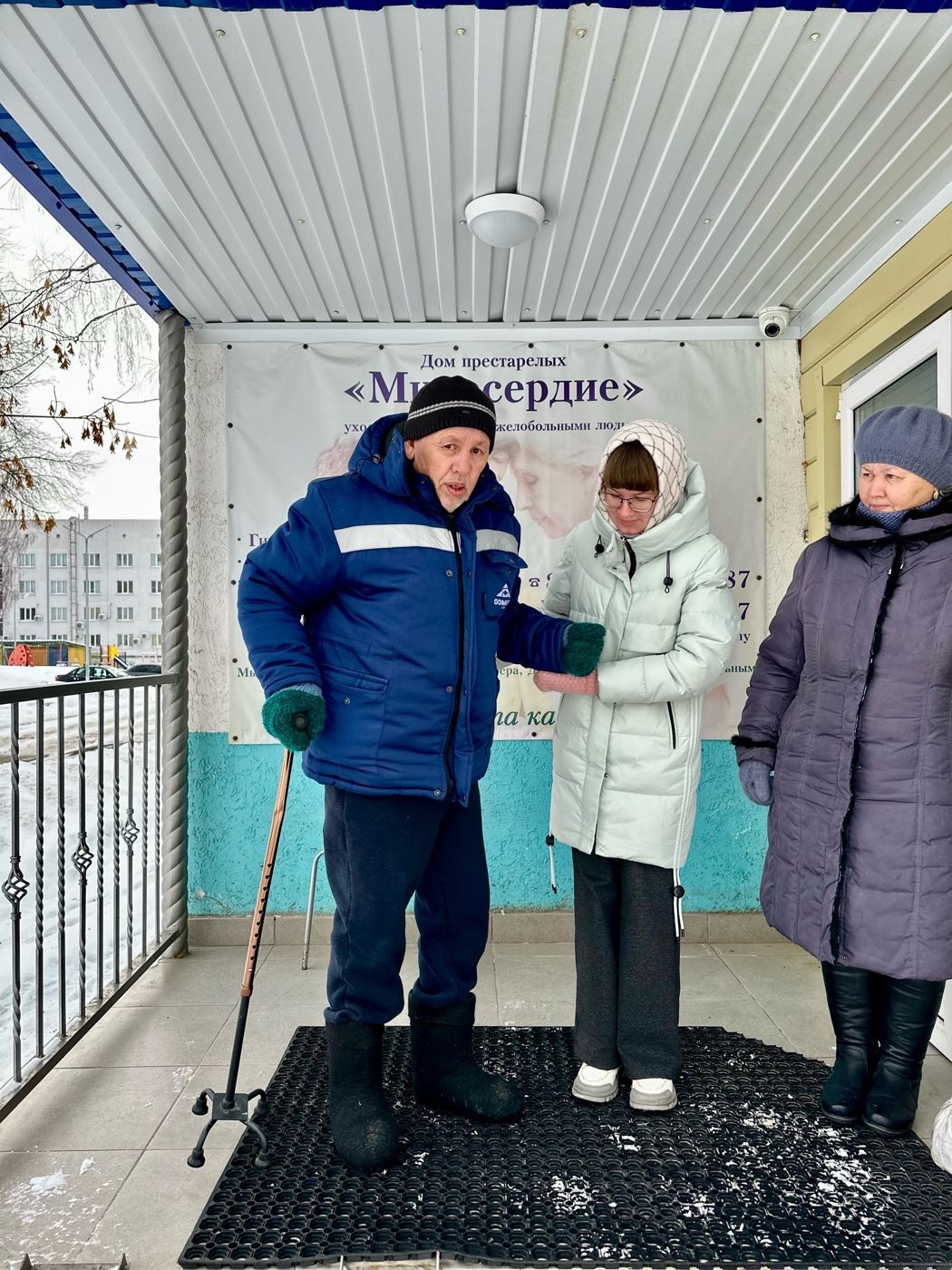 Подопечный с тростью и сотрудницы на крыльце пансионата